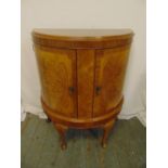 A mahogany and satinwood demi-lune cabinet with hinged doors on four scroll legs