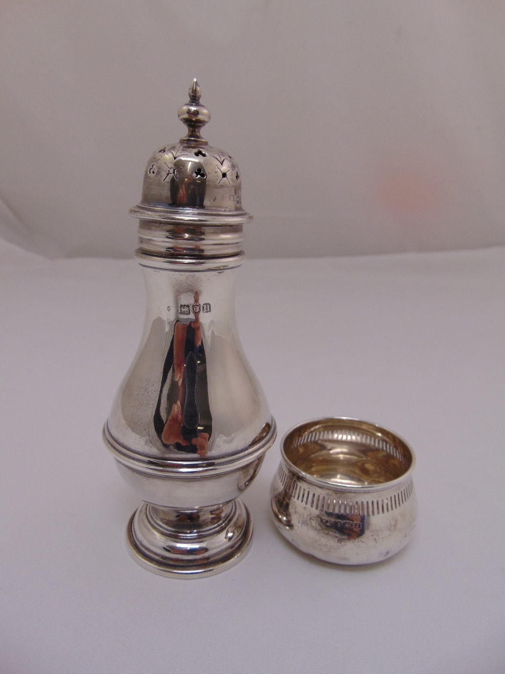 A silver sugar sifter of baluster form with ribbed waist, London 1915, 18cm high and a silver salt