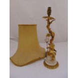 An ormolu and marble table lamp with applied putti holding a trident on tapering cylindrical base to