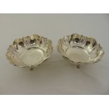 A pair of silver nut dishes, lobbed bar pierced sides on three scroll legs, Birmingham 1931,