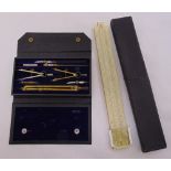 A cased slide rule and a cased set of drafting instruments