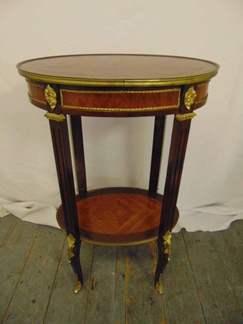 A French oval mahogany and kingswood parquetry and gilt metal occasional table on four cabriole