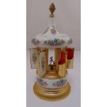 A ceramic and gilded metal cigarette dispenser in the form of a carousel with musical movement, 36cm