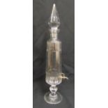 A glass decanter tapering cylindrical with drop stopper and metal spigot on raised circular base,