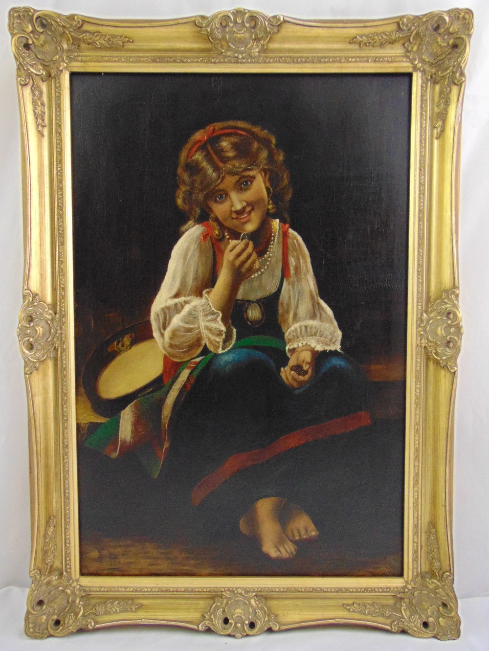 A framed oil on canvas of a seated girl with a tambourine, monogrammed FL and dated 1880 bottom