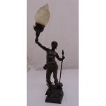 A spelter lamp stand in the form of a warrior holding a spear and supporting a frosted glass flame