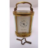 Mappin and Webb miniature brass carriage clock of oval form with white enamel dial, Roman