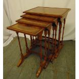 A nest of four rectangular burr walnut side tables on turned tubular supports and outswept bracket