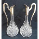 A pair of continental cut glass pear shaped ewers with white metal mounts and scroll handles,