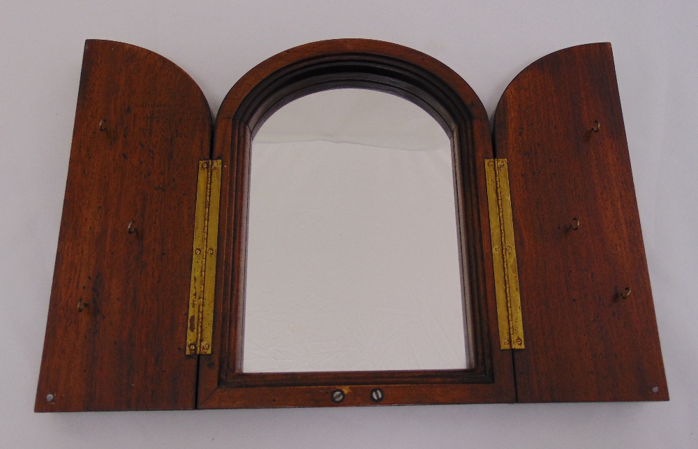 A mahogany wall mirror, arched top the hinged doors set with key hooks, 30 x 22cm