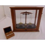 A set of brass balance scales in glazed wooden case to include a cased set of weights, 40 x 45.5 x
