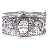 An Antique Chinese silver hinged bangle, openwork body with relief applied dragon decoration and