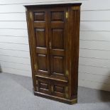 An 18th century floor standing panelled oak corner cupboard, with fluted corners