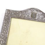 An Indian unmarked silver-fronted photo frame, with relief embossed foliate decoration and