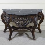 An ornate Rococo style carved walnut console table with shaped marble top, carved and pierced floral