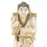 A Japanese ivory okimono, man carrying kindling wood and a book, Meiji Period, signed under base,