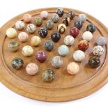 A solitaire board, diameter 32cm, together with a set of marble and hardstone balls, diameter 25mm