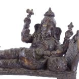 A large reproduction Indian heavy gauge patinated bronze figure of Ganesh reclining on a couch,