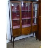 An Edwardian mahogany and satin-strung display cabinet, with glazed bow-front door, raised on square