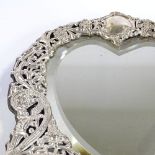 A late Victorian silver-fronted heart-shaped dressing table strut mirror, relief embossed and