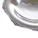 A German silver circular dish, cast floral border and three scrolled feet, by H Kose, diameter 17.