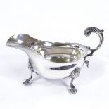 A late Victorian silver sauce boat, scalloped rim and scrolled acanthus leaf C handle on hoof