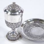 A Continental unmarked white metal lidded goblet and stand, relief embossed floral decoration,