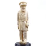 A carved ivory figure of a man in military uniform, unsigned, on turned ebony base, overall height
