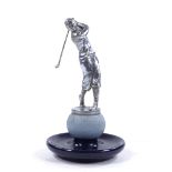 A chrome plate bronze golfer car mascot, by Louis Lejeune, circa 1935, mounted on a stoneware