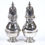 A pair of Edwardian silver sugar casters, plain baluster form with banded body and embossed