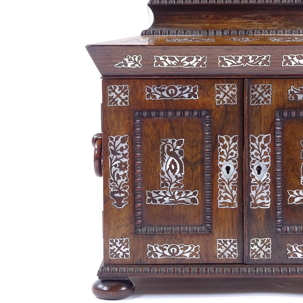 An early 19th century rosewood and mother-of-pearl marquetry inlaid sewing cabinet, the lid having a