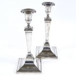 A pair of George V silver table candlesticks, square form with stepped base, reeded border and