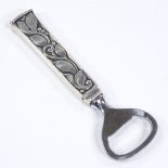 An Evald Nielsen Danish silver handled bottle opener, relief leaf and berry decoration with steel