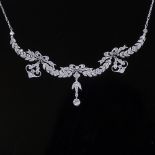 An Art Deco style unmarked platinum diamond festoon necklace, bow and leaf swag design set with