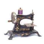 A 19th century German child's black painted cast-iron sewing machine, gilt floral decoration, length