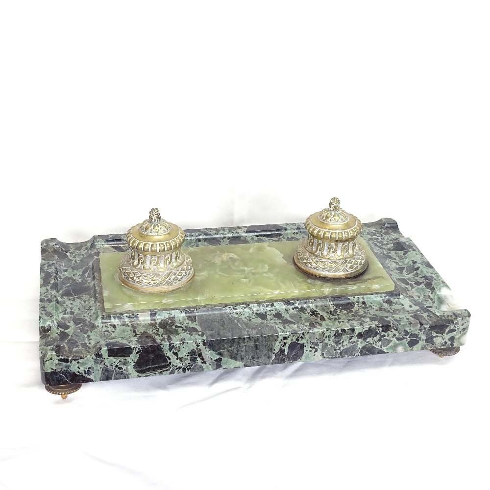 A large polished green marble desk stand, with double brass inkwells and inset central onyx panel,