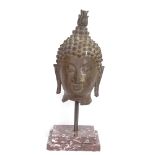 An Oriental polished bronze Buddha head, on red veined marble plinth, overall height 40cm