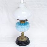 An Edwardian brass oil lamp, with blue milk-glass floral font and polished black ceramic base,