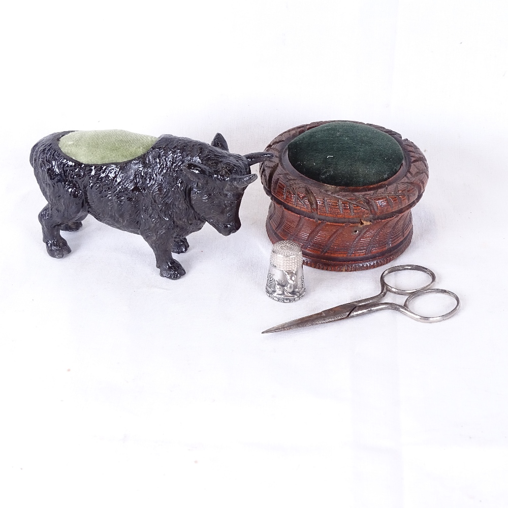 A painted bull pin cushion, a sterling silver thimble, turned wood pin cushion etc