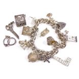 A silver curb link heart-lock charm bracelet, with 13 silver charms, including the shrinking