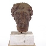 A life-size carved stone head, possibly an Antiquity, wearing a laurel wreath, mounted on modern