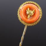 A Victorian unmarked gold carved coral foxhead hunting design stick pin, with rope twist surround,