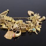 A heavy 9ct gold triple curb link heart-lock charm bracelet, with many charms ranging from 9ct to