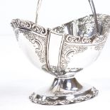 A late Victorian silver swing-handled basket, oval form with relief embossed foliate decoration