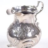 An 18th century Dutch silver cream jug, scalloped rim with scroll acanthus leaf handle and relief