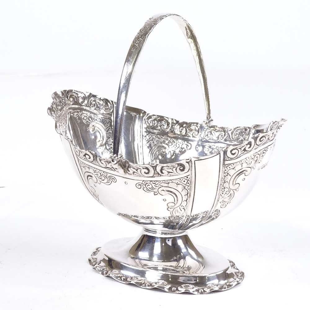 A late Victorian silver swing-handled basket, oval form with relief embossed foliate decoration - Image 2 of 3