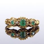 An unmarked gold emerald and diamond ring, relief scrollwork shoulders and bridge, setting height