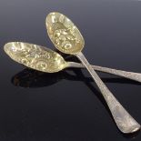 A pair of George II silver berry spoons, bright-cut engraved foliate handles with gilt embossed