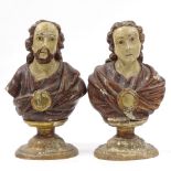 A pair of 18th century carved painted and gilded wood busts of saints, on oval wooden bases,