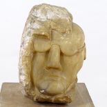 A life-size relief carved alabaster rock fragment in the form of a man's head wearing glasses,